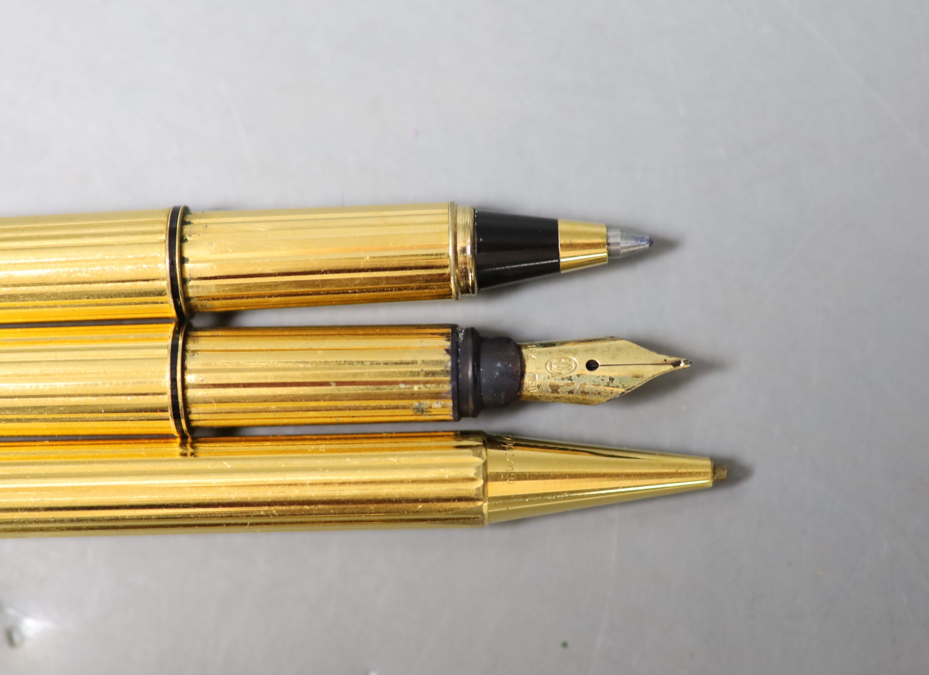 A Cartier gilt metal fountain pen, ball point pen and propelling pencil